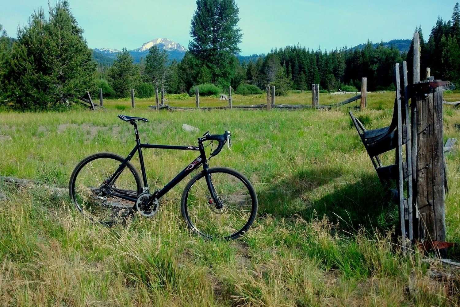Bike leaning against fence with meadow and lassen peak in bacground