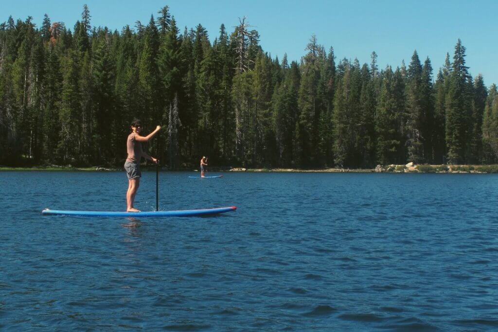 woman paddle boarding on lake with other paddle boarder in distance