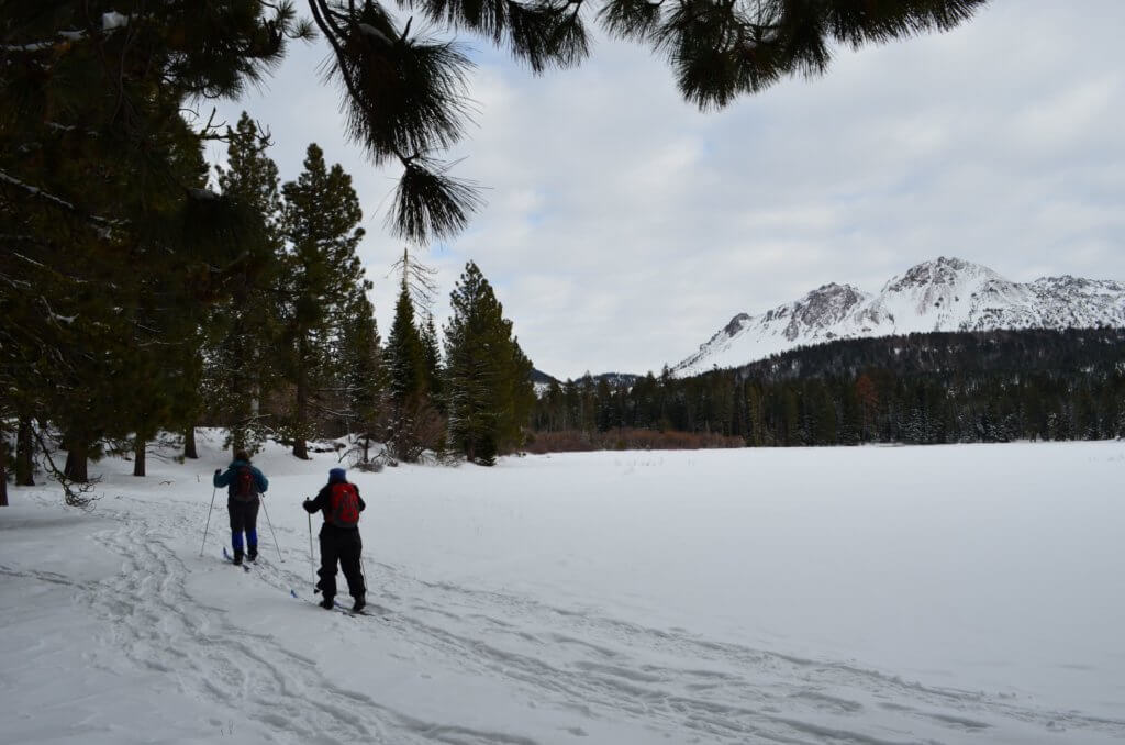 2 cross country skiers going by snow covered manzanita lake