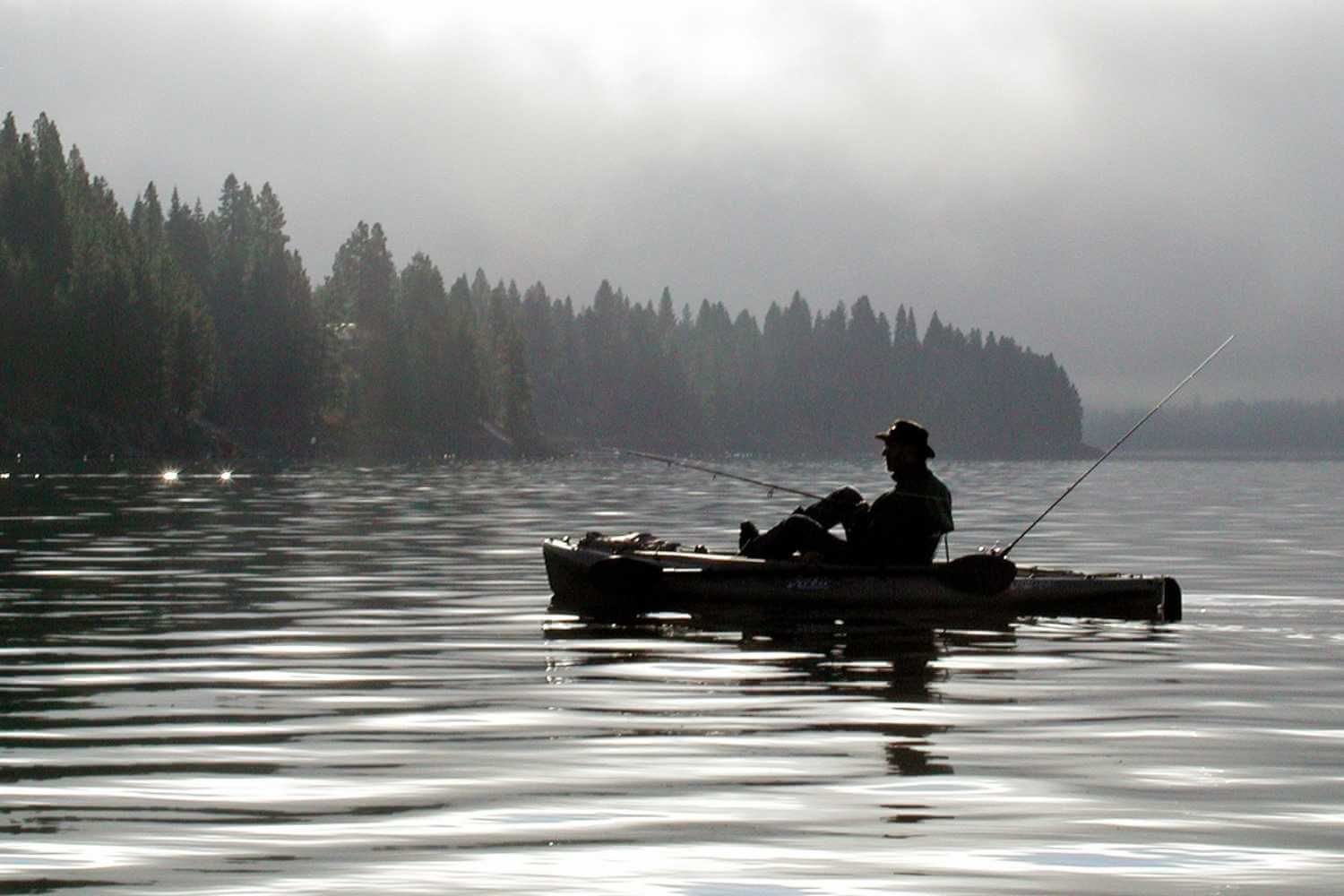 Man fishing early morning from small watercraft on lake almanor