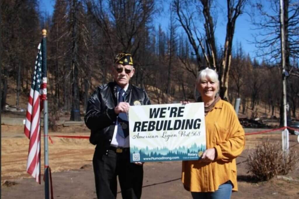 Two people holding sign We're Rebuilding Greenville