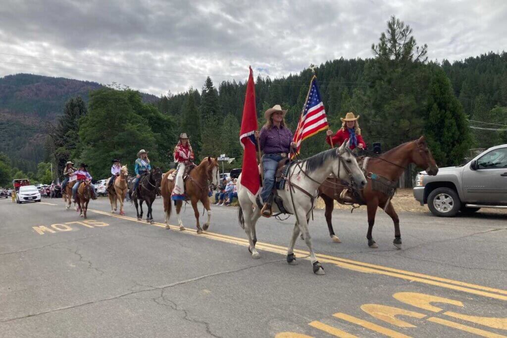 Group of horseback riders carrying American Flag in the Taylorsville 4th of July PArade