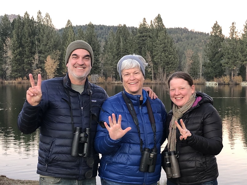 Three smiling birders with lake in background