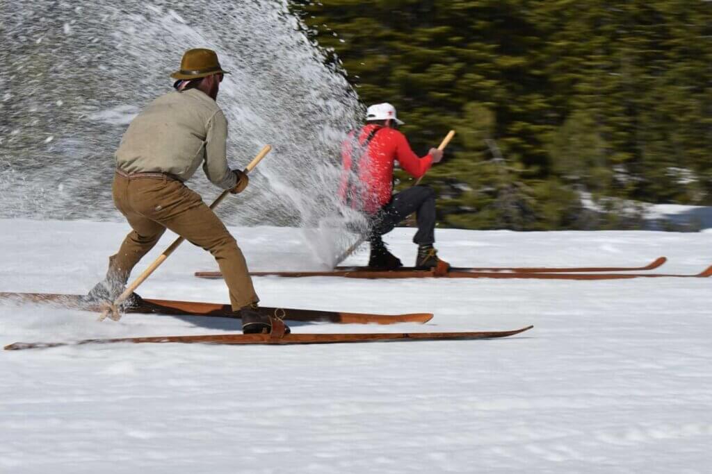 Skiers slowing down at the end of a race, making a rooster tail