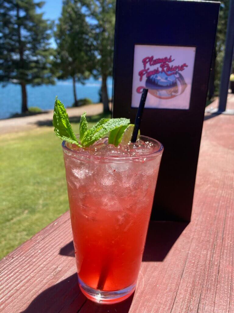 view of Lake Almanor from deck of plumas pines, Cocktail and menu sitting on railing.